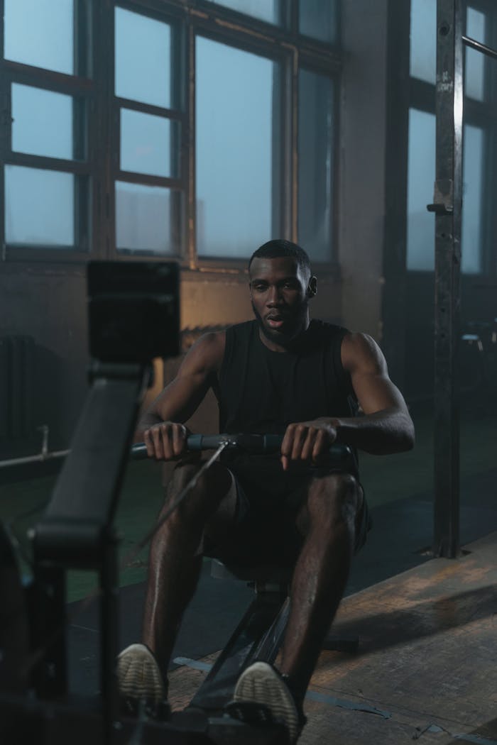 Man concentrating on an intense rowing workout inside a gym, embodying strength and determination.
